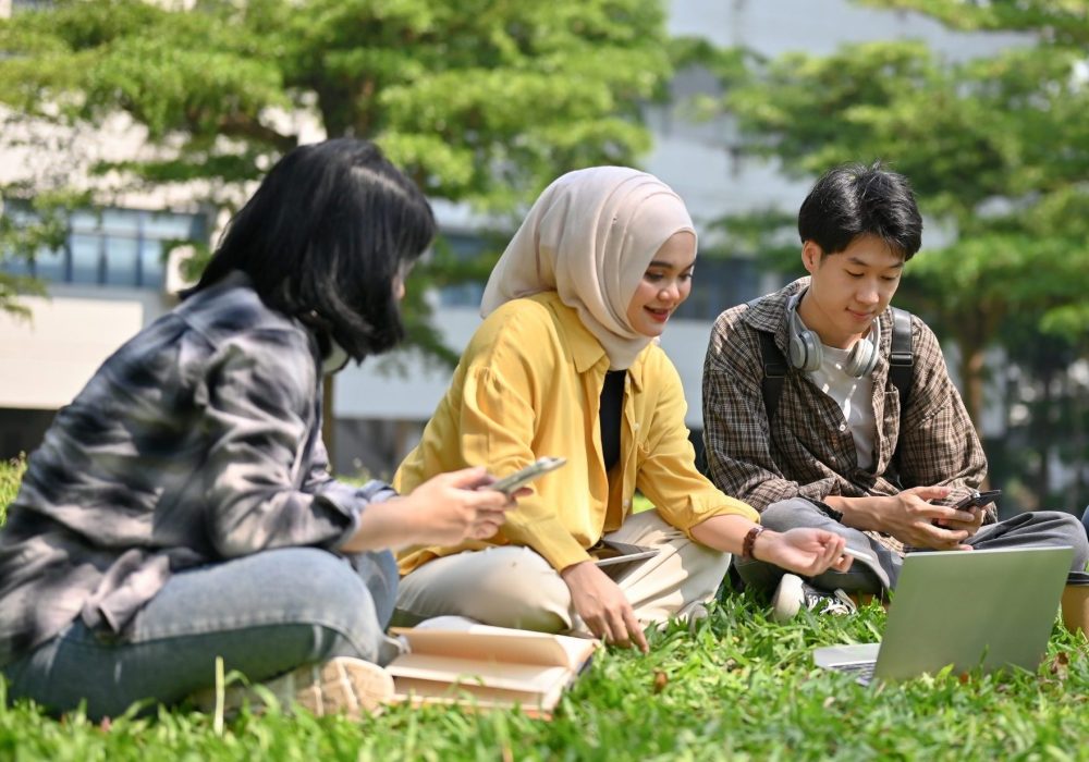 A group of smart young Asian-diverse college students are discussing and brainstorming on their school project in the campus park together. Uni-lifestyle and friendship concept